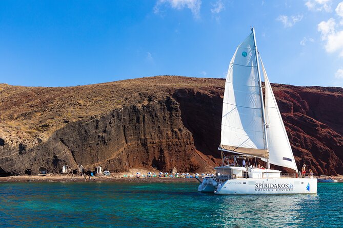 Santorini Private Catamaran Cruise with BBQ, Open Bar & Transfers - Red Beach, where the cliffs set the tone